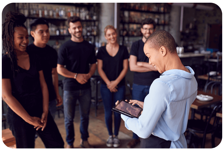 A manager uses a tablet during a staff briefing in a business multi-location setup in Phoenix, AZ.