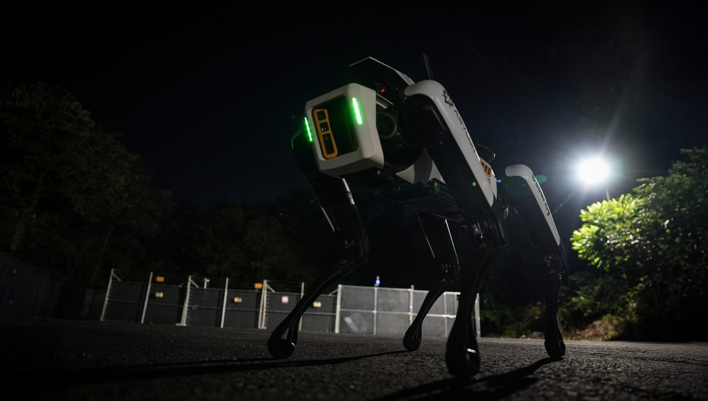 DroneDog robot patrolling a fenced perimeter at night